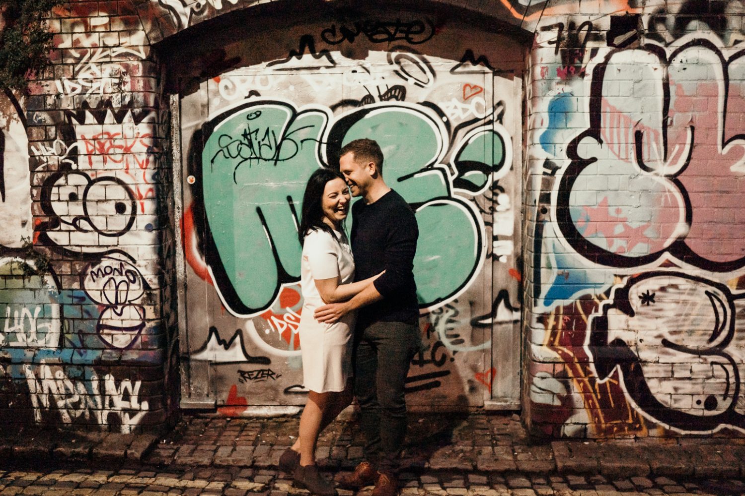 engaged couple hugging in stokes croft graffiti wall in bristol