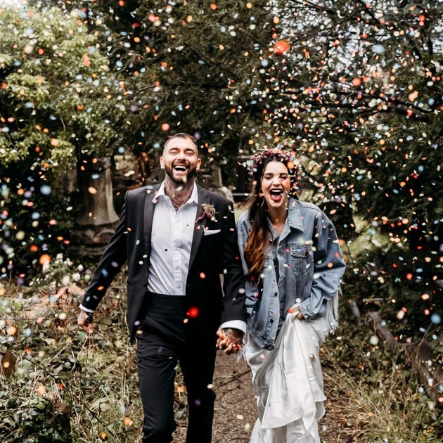 alternative bride and groom walking through confetti tunnel