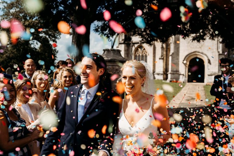 quirky bride and groom walking through confetti tunnel