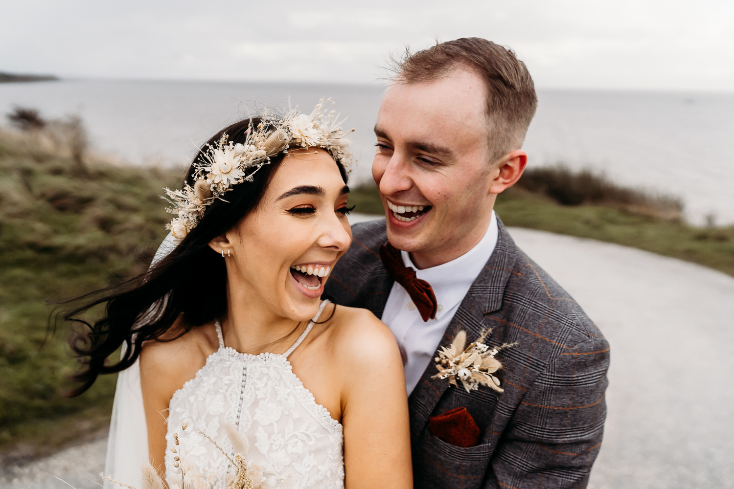 fun young bride and groom hugging at liverpool beach